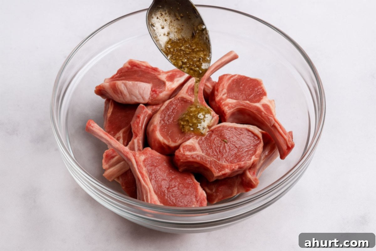 Traditional Greek Lamb Chops 6 A spoonful of marinade being poured over raw lamb chops in a glass bowl, ready to be coated.