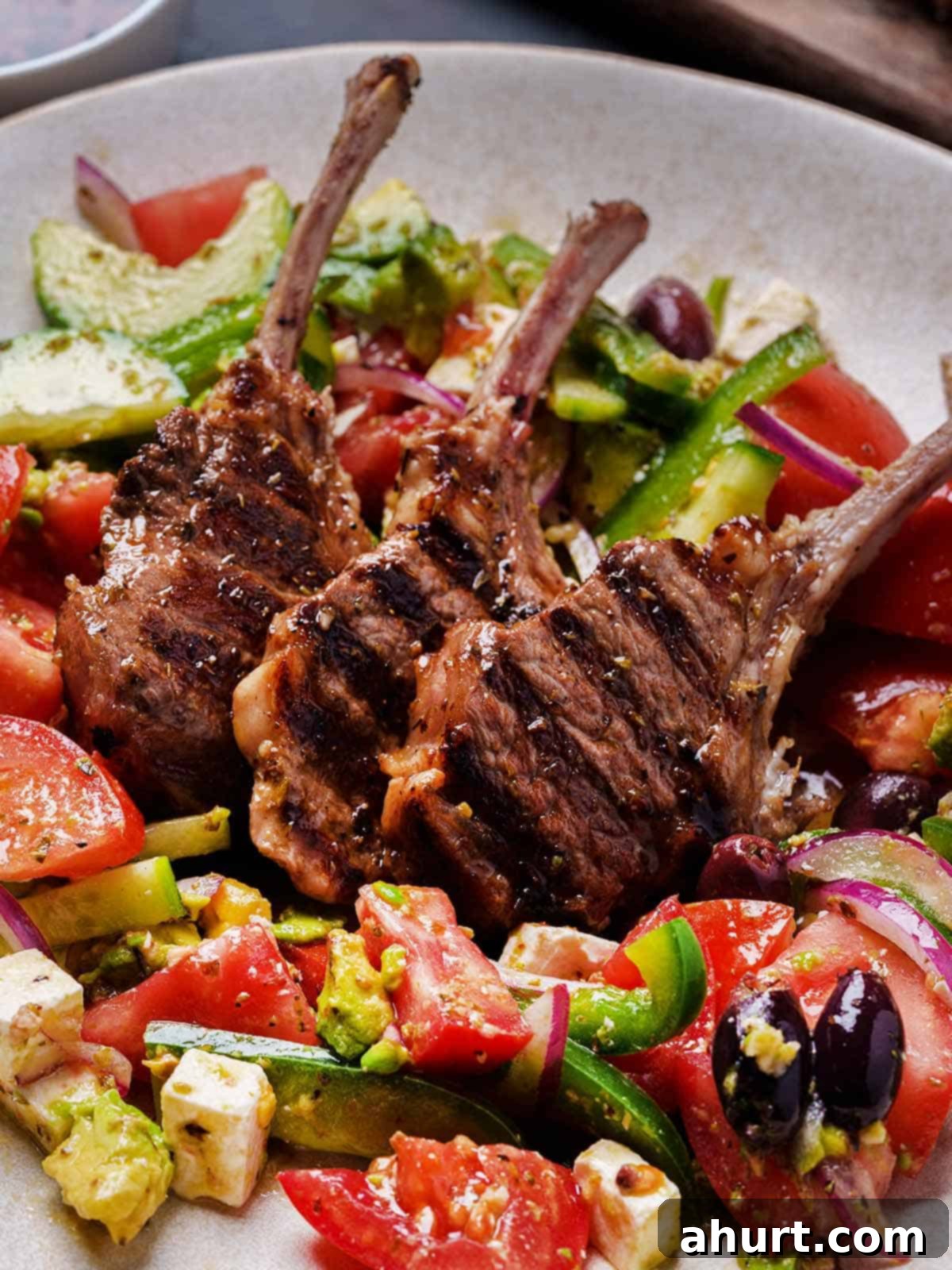 Traditional Greek Lamb Chops 8 greek lamb chops perfectly seared and juicy sits in the middle of a salad mix in a bowl