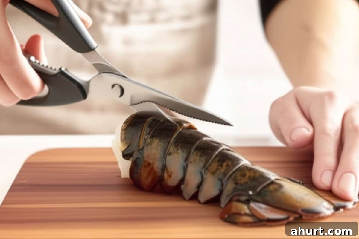 Succulent Broiled Lobster Tails 7 Hand with kitchen shears cutting through the top shell of the lobster tail.