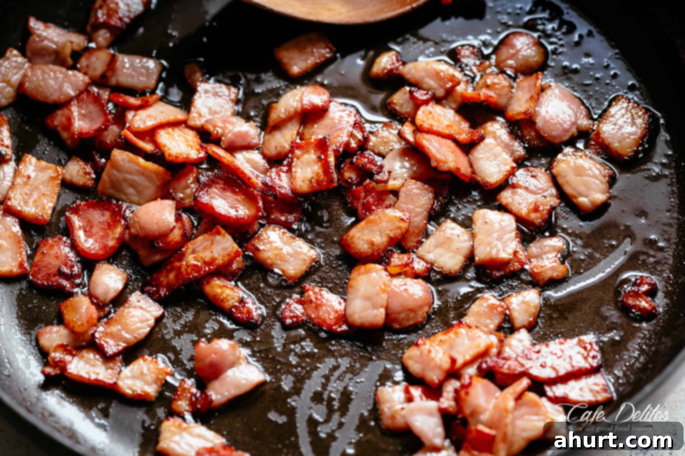 Beef Bourguignon by Julia Child 4 Bacon frying in a black pan with a wooden spoon