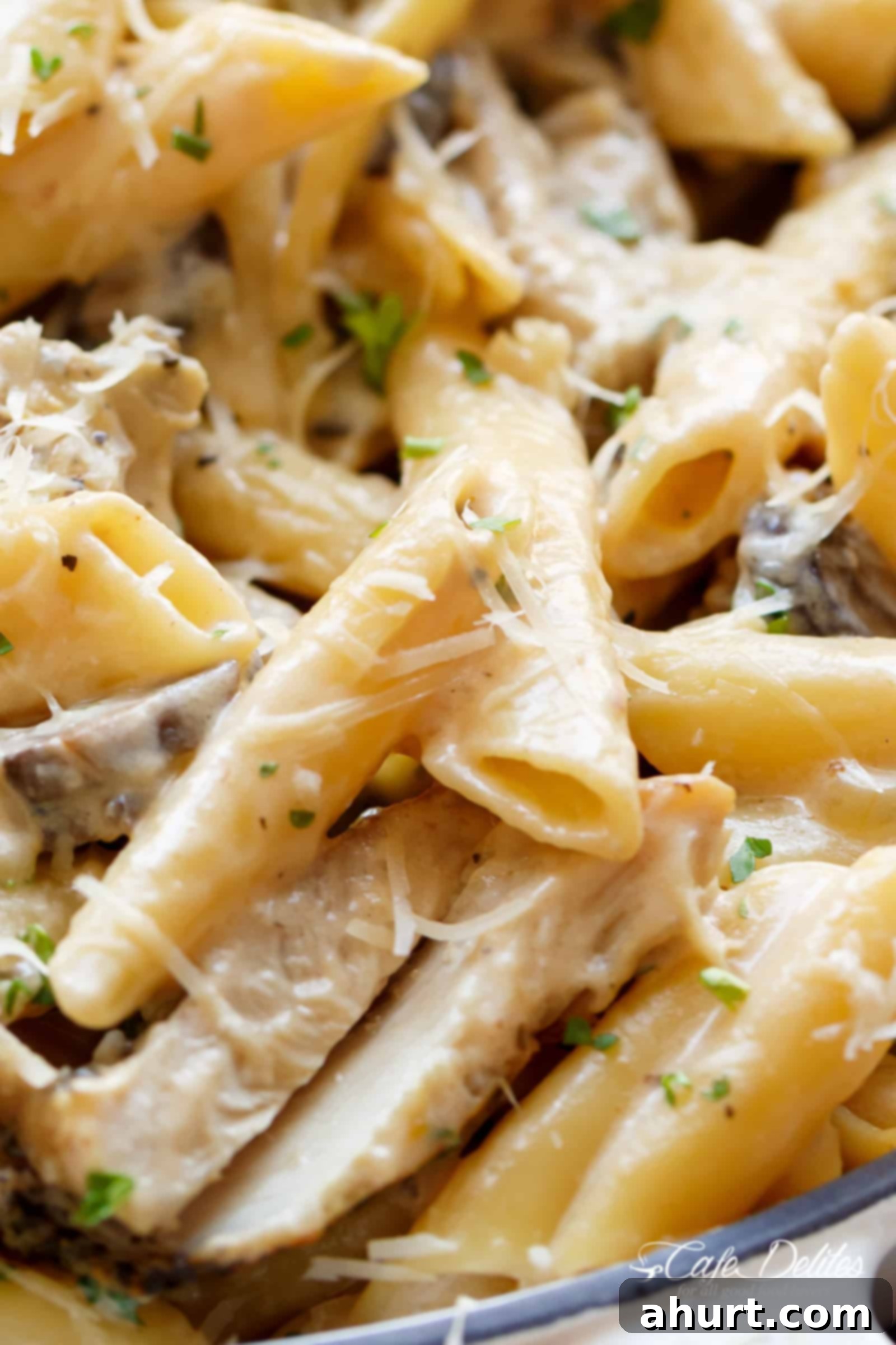 Creamy Garlic Parmesan Chicken Alfredo is all cooked in ONE POT is ready and on the table in less than 20 minutes! | cafedelites.com One-Pot Creamy Garlic Parmesan Chicken Alfredo in a large pot with a serving spoon, highlighting the rich, thick sauce and tender pasta.