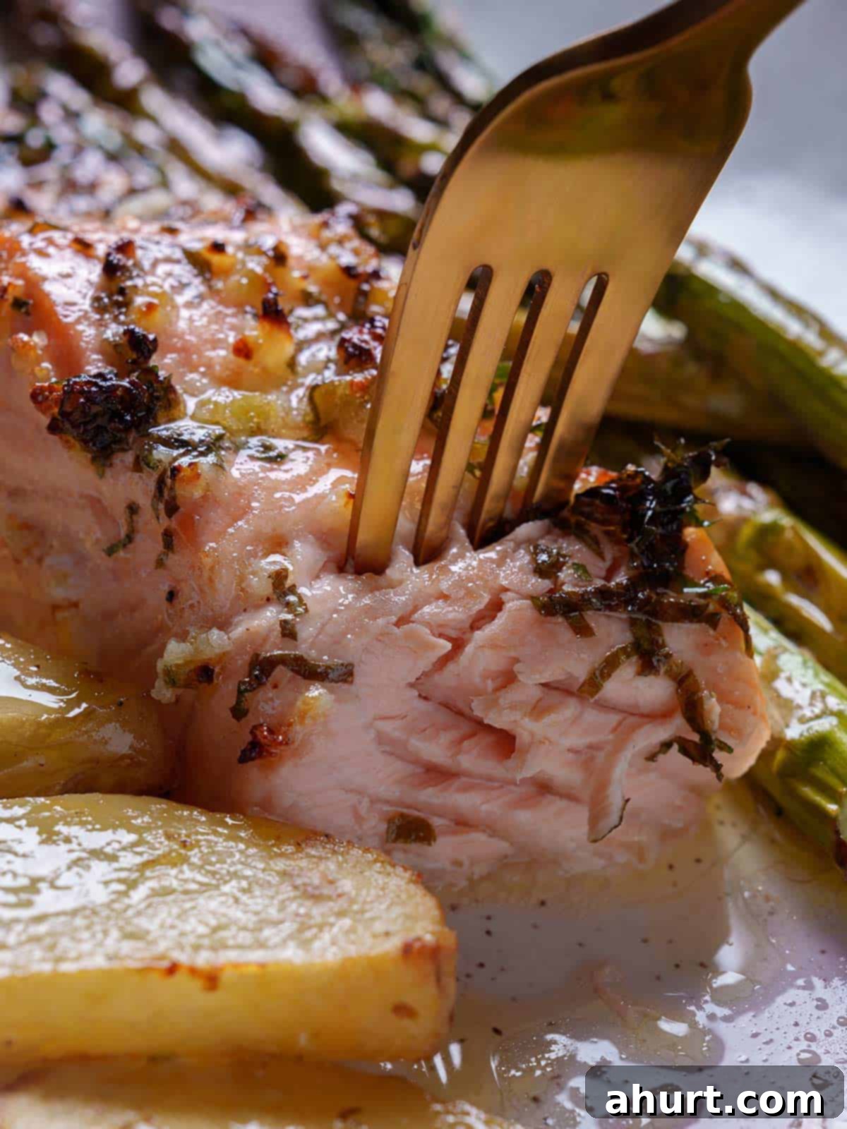 Decadent Garlic Butter Salmon 2 Close-up image of a tender and juicy salmon darne, complemented by asparagus and baked potatoes.