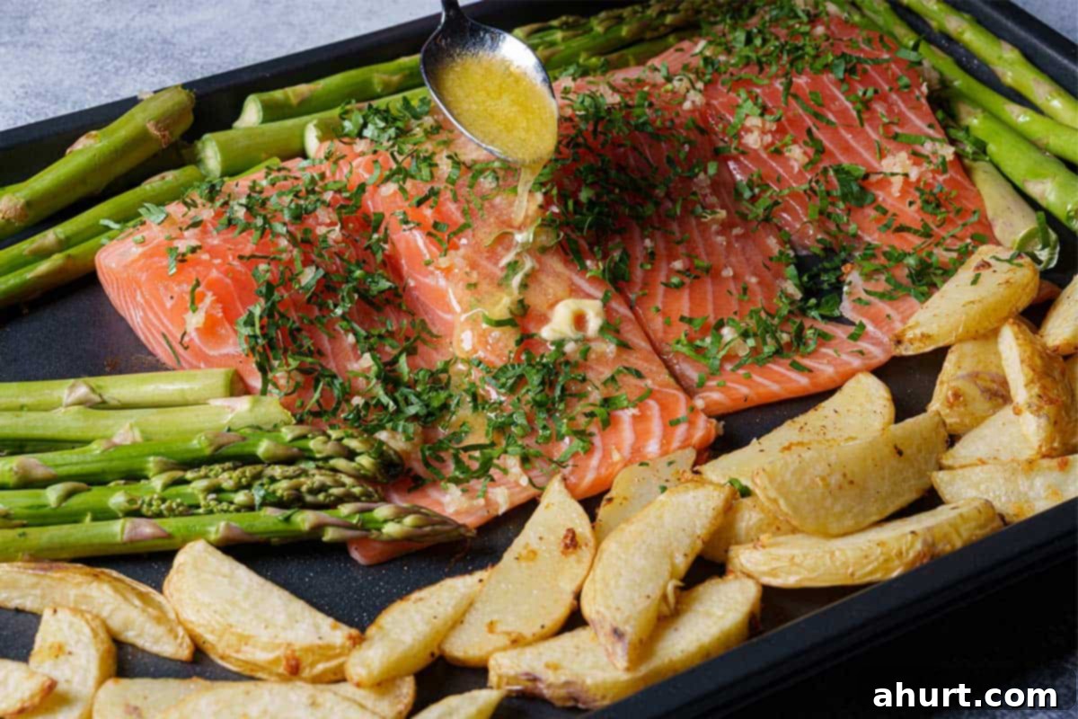 Decadent Garlic Butter Salmon 6 Image of lemon juice and melted butter being poured over the salmon on a baking sheet.