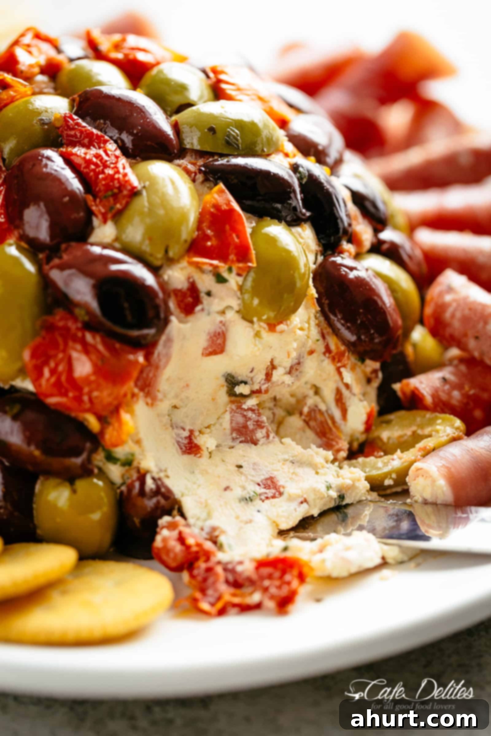 Antipasto Cheese Ball | cafedelites.com A bite taken from Antipasto Cheese Ball on a plate, showing its delicious texture