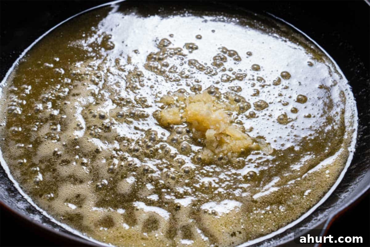 Golden Honey Garlic Butter Carrots 6 Image of minced garlic added to a skillet with melting butter.