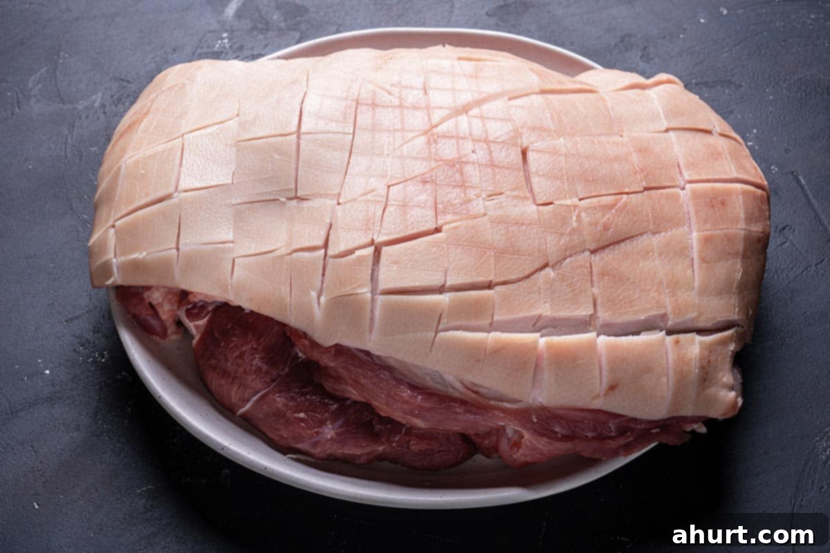 Golden Crackle Pork Roast 4 Close-up of pork rind being carefully scored with a sharp knife to prepare for crackling.