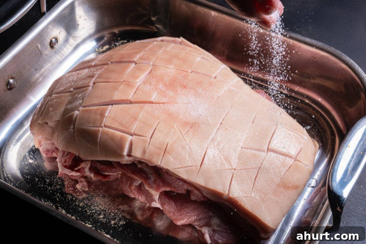 Golden Crackle Pork Roast 5 Hands rubbing garlic powder and salt into the underside of a pork shoulder before roasting.
