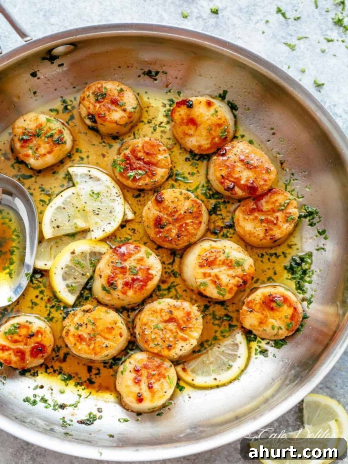 Lemon Garlic Butter Scallops in less than 10 minutes | cafedelites.com Golden, seared scallops in a pan with shallow layer of garlic butter, garnished with herbs and several lemon wedges to one side.