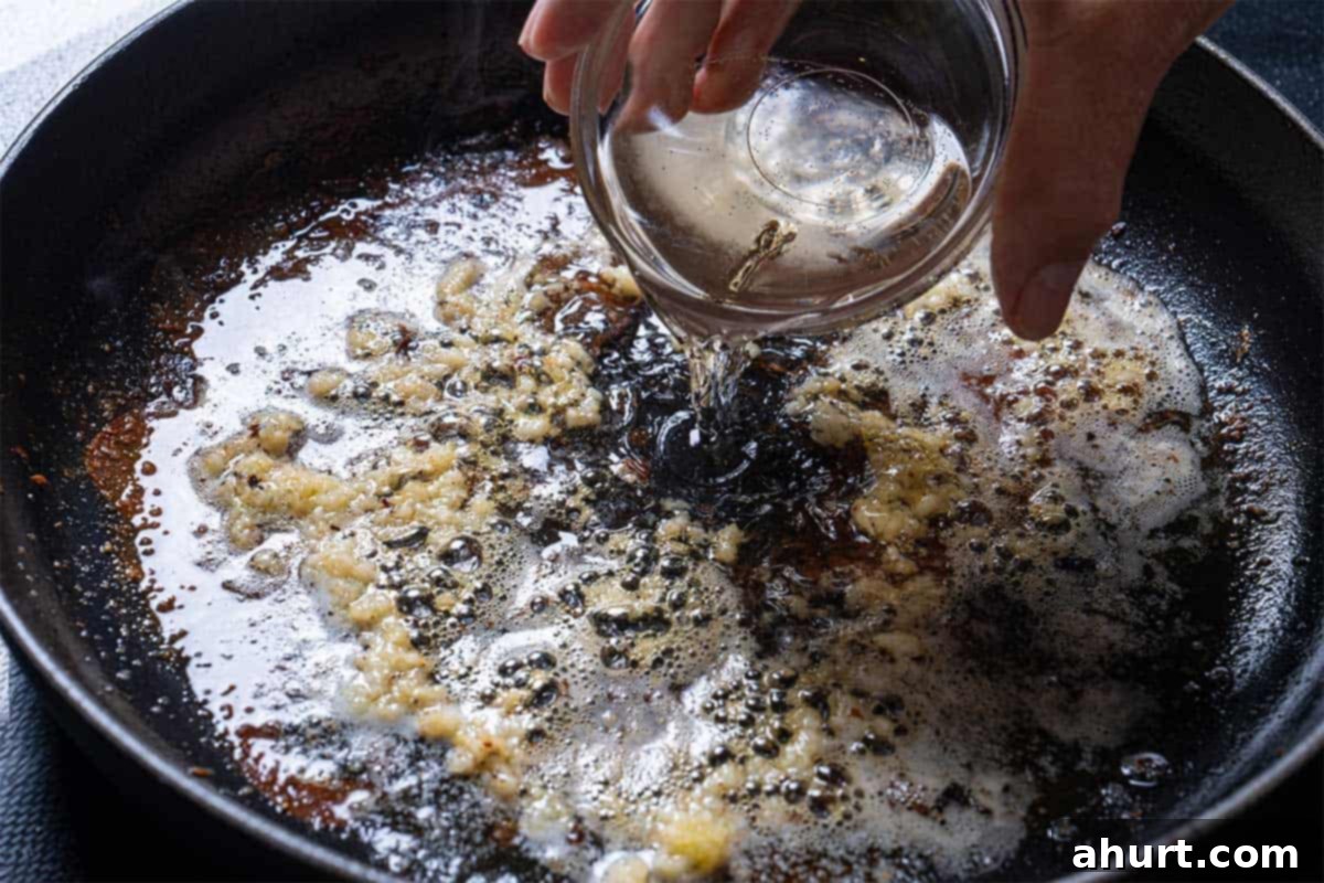 Pan-Seared Golden Garlic Butter Scallops 7 Image of wine being added to the frying pan.