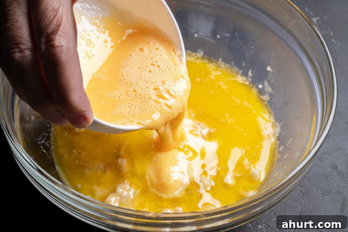 The Ultimate Chocolate Chip Banana Bread 6 egg mixture being poured into dry mixed ingredients