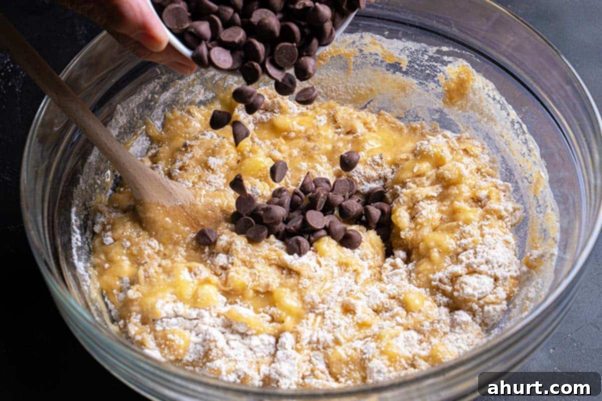 The Ultimate Chocolate Chip Banana Bread 7 chocolate chips being poured into batter mix
