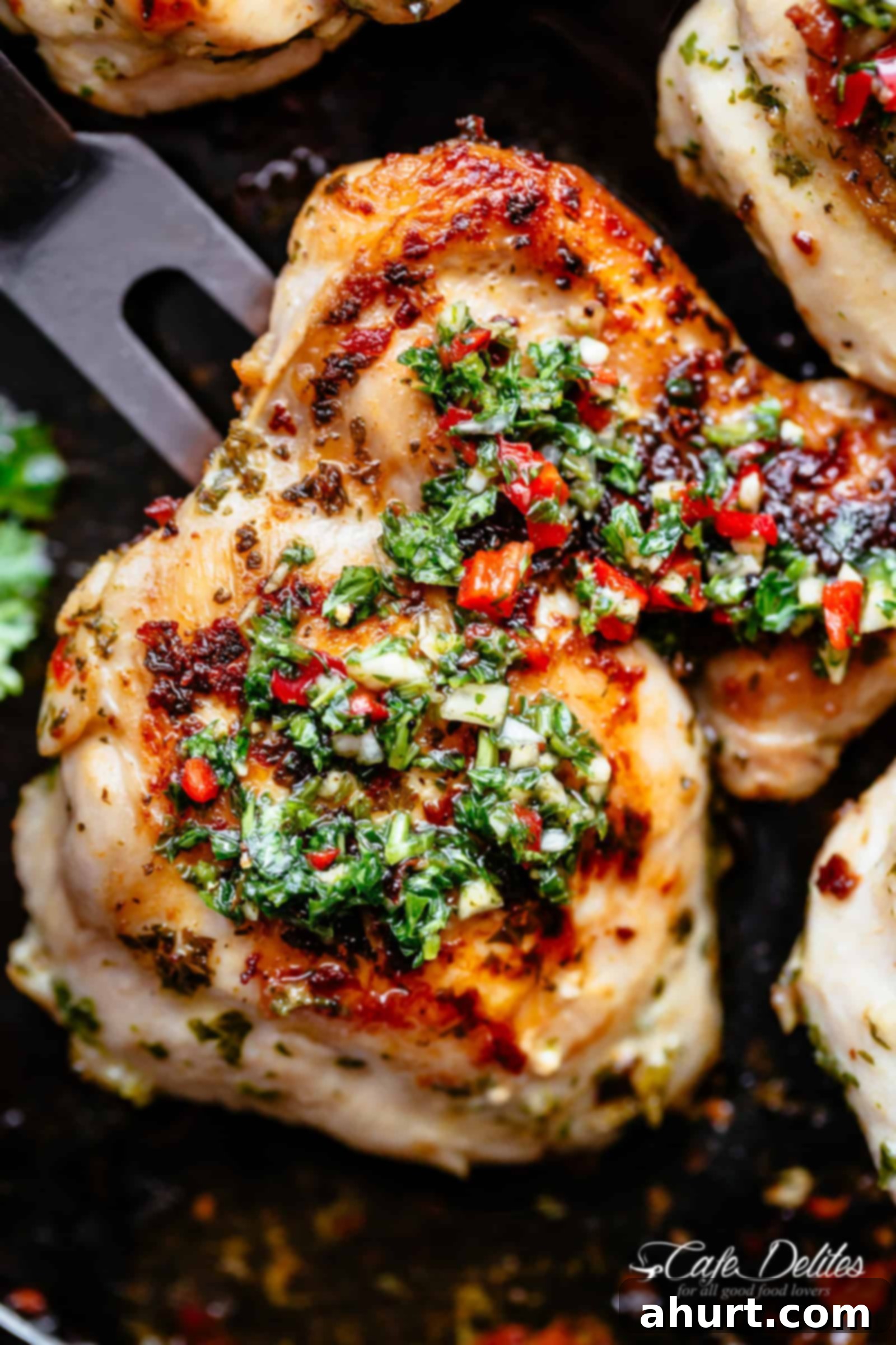 Golden roasted chicken on a black pan with Chimichurri on top.