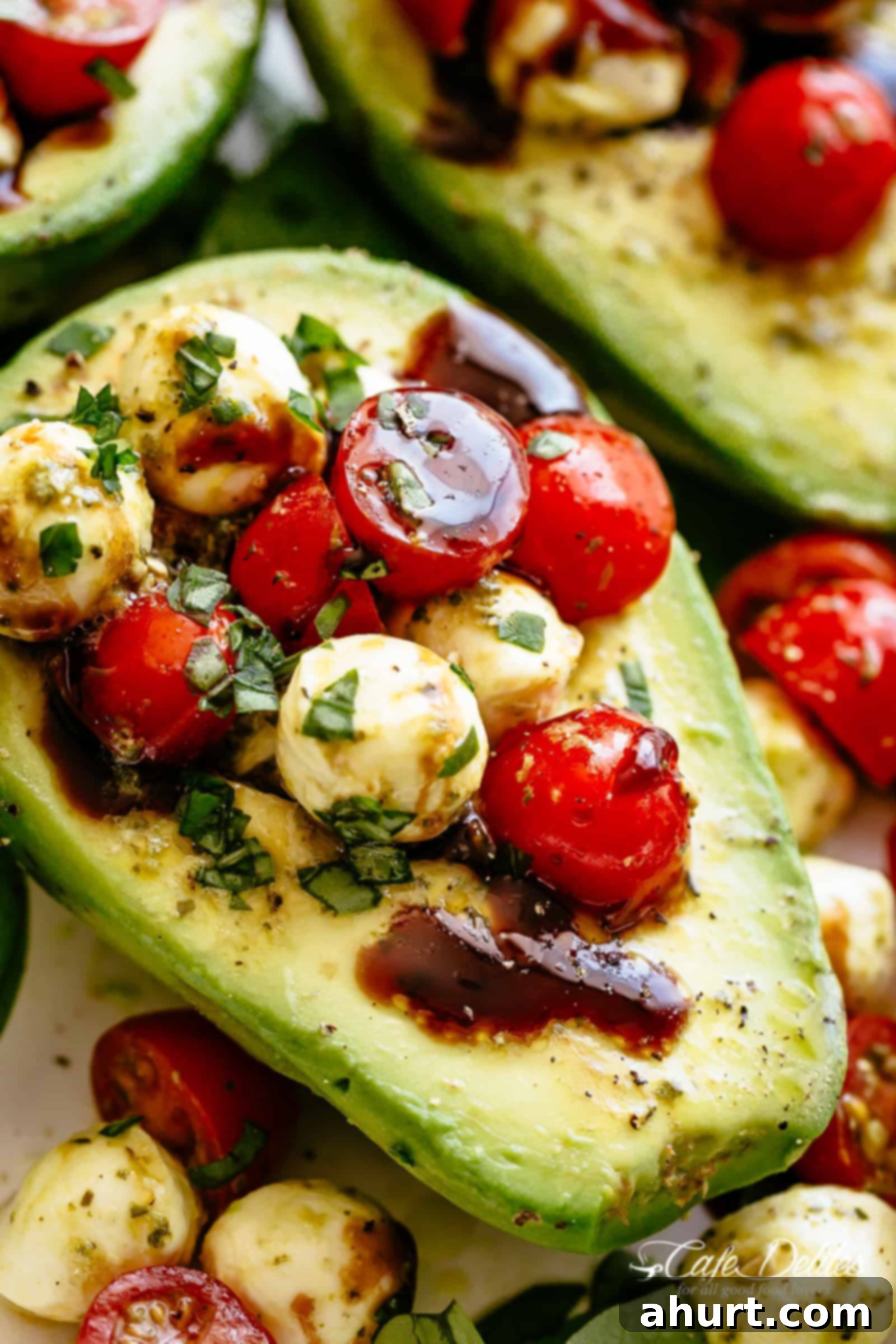 Caprese Stuffed Avocados | cafedelites.com Top view image of freshly prepared Caprese Stuffed Avocado halves, drizzled with balsamic glaze and garnished with fresh basil.