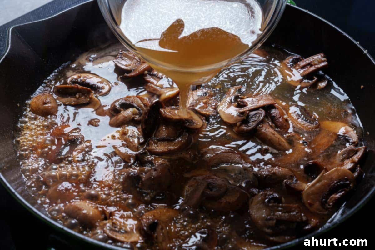 Velvety Chicken Marsala Made Simple 7 An image of stock being added to the mushrooms.