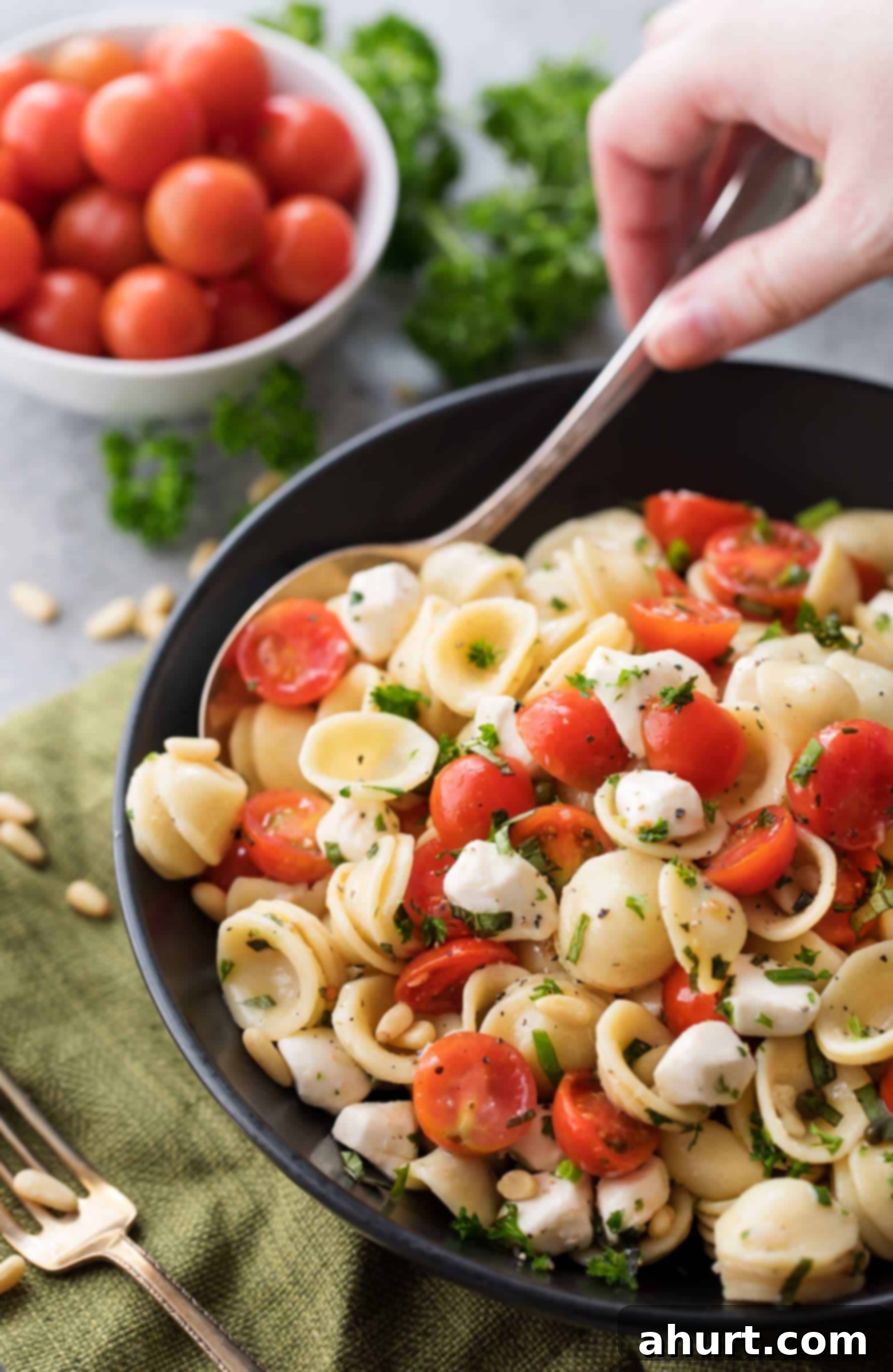 Caprese pasta salad | cafedelites.com A large bowl of Caprese pasta salad featuring vibrant cherry tomatoes, fresh mozzarella balls, and green basil, all mixed with pasta and drizzled with vinaigrette.