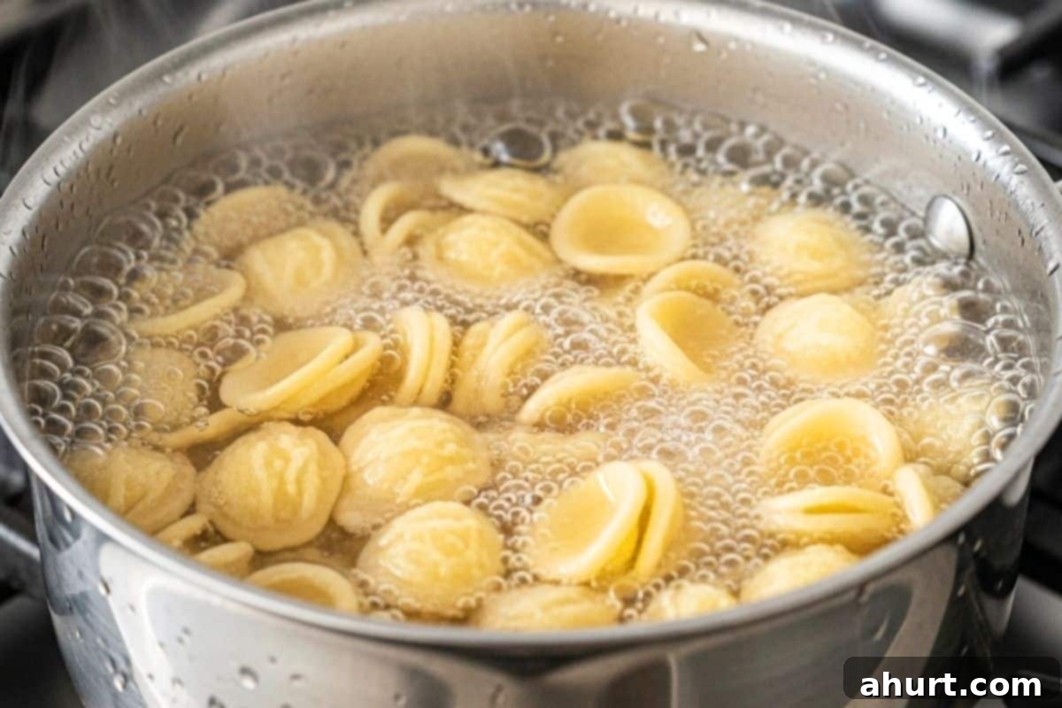 Fresh Caprese Pasta Salad 5 Orecchiette pasta cooking in a pot of boiling water on a stovetop.