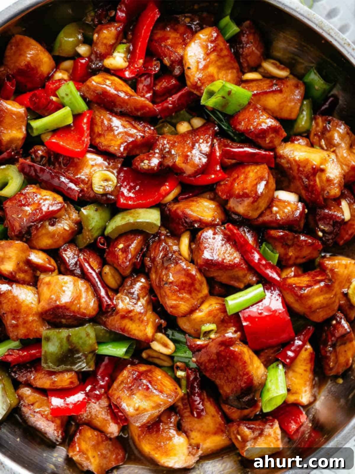 Kung Pao Chicken | cafedelites.com Close up image of Kung Pao Chicken in a sticky Kung Pao sauce with green and red chopped vegetables picked in with chicken pieces.