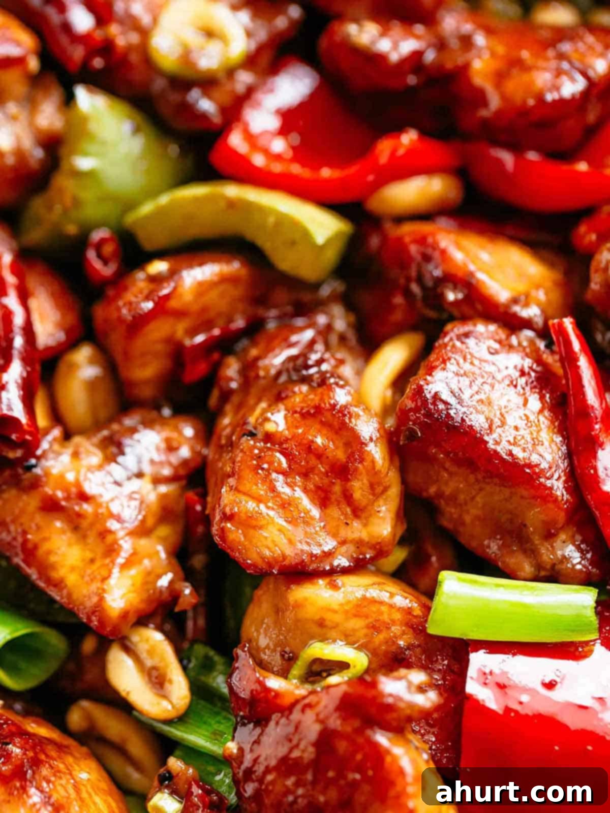 Kung Pao chicken recipe! | cafedelites.com Close up image of Kung Pao Chicken in a sticky Kung Pao sauce with green and red chopped vegetables picked in with chicken pieces.
