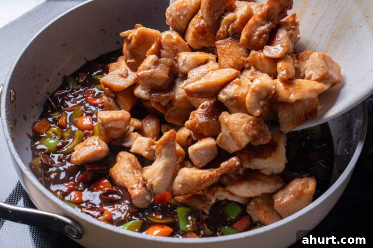 Kung Pao Chicken 8 garlic, ginger, chili diced peppers (capsicums) and Sichuan peppercorns and sauce mixture with cooked chicken being poured in