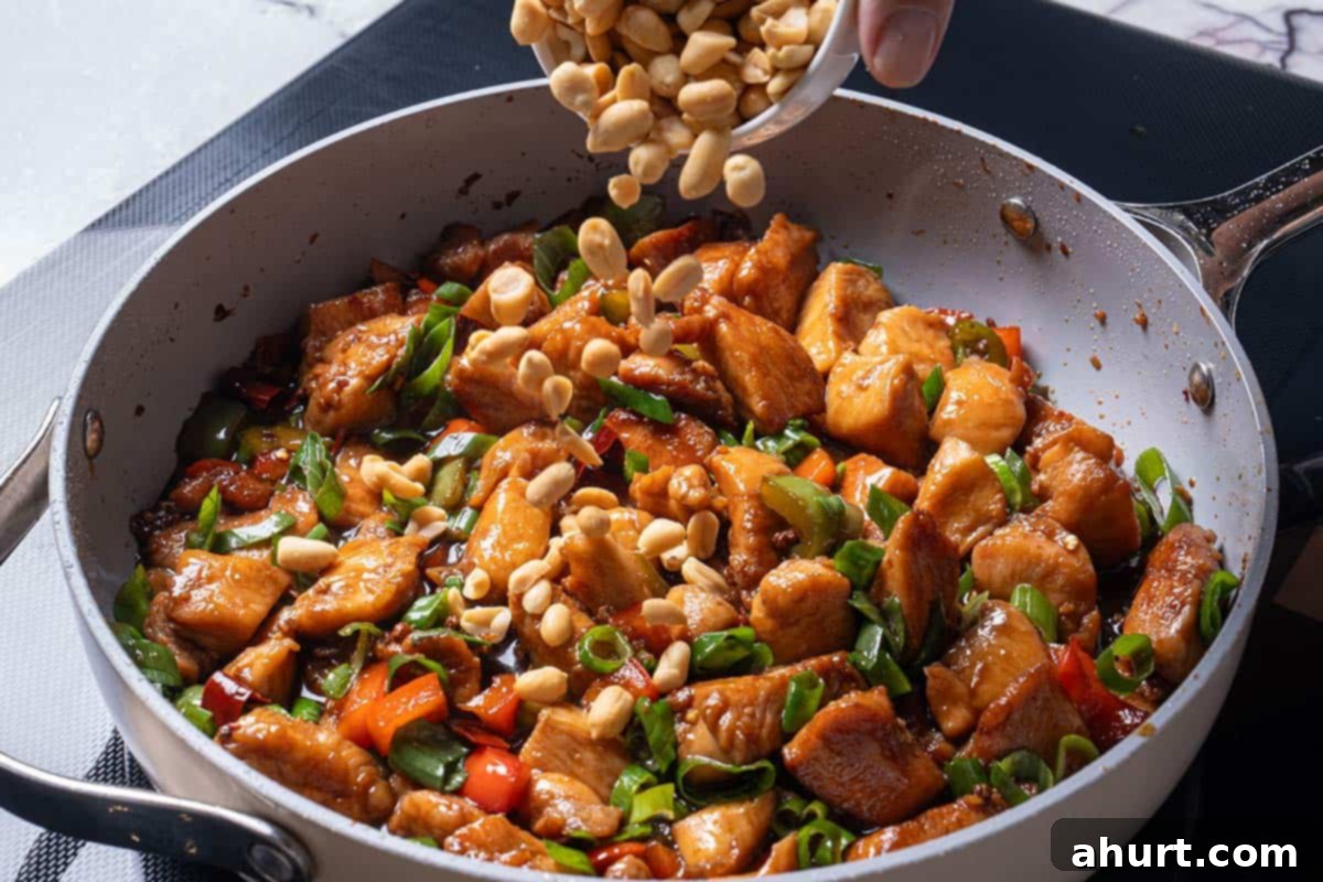 Kung Pao Chicken 9 garlic, ginger, chili diced peppers (capsicums) and Sichuan peppercorns and chicken with peanuts being poured over