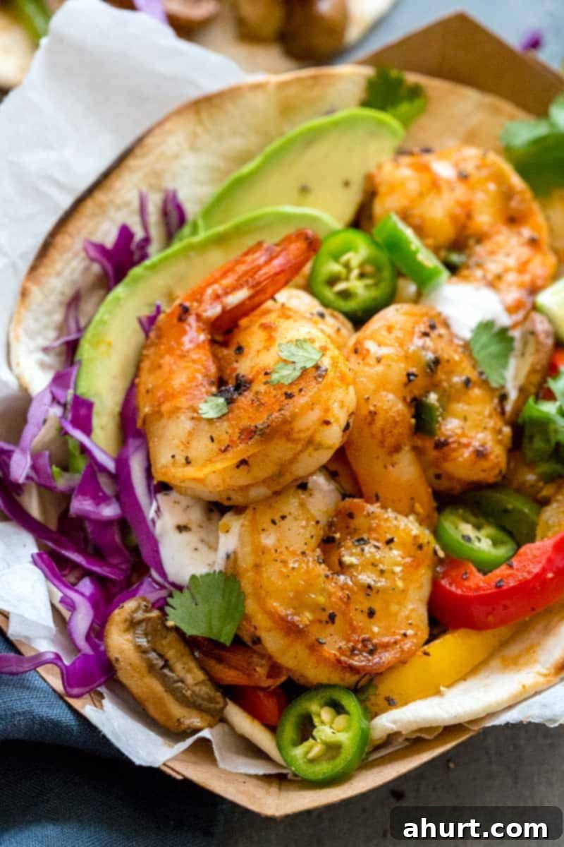 Fiery Shrimp Fajitas 2 close up image of spicy shrimp fajitas overflowing from a tortilla, garnished with cilantro and lime.