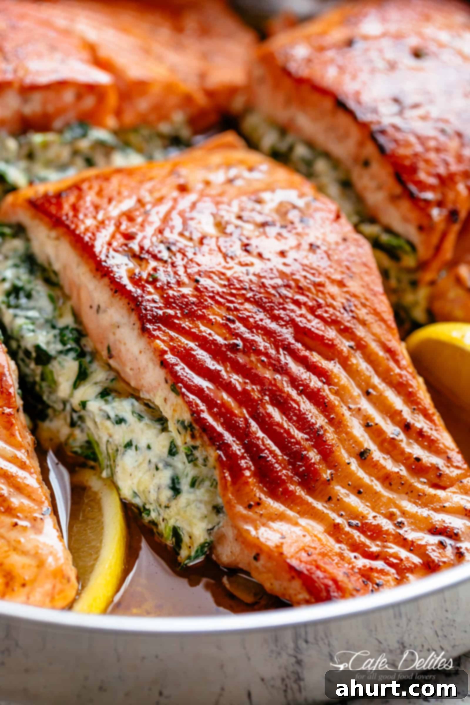 Creamy Spinach Stuffed Salmon | cafedelites.com A close up image of a fillet of creamed spinach stuffed salmon in a silver pan with lemon slices