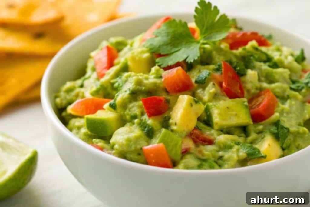 Crafting Irresistible Guacamole 4 Mashed avocado, combined with the aromatics, lime juice, cilantro, and black pepper in a bowl, being stirred.