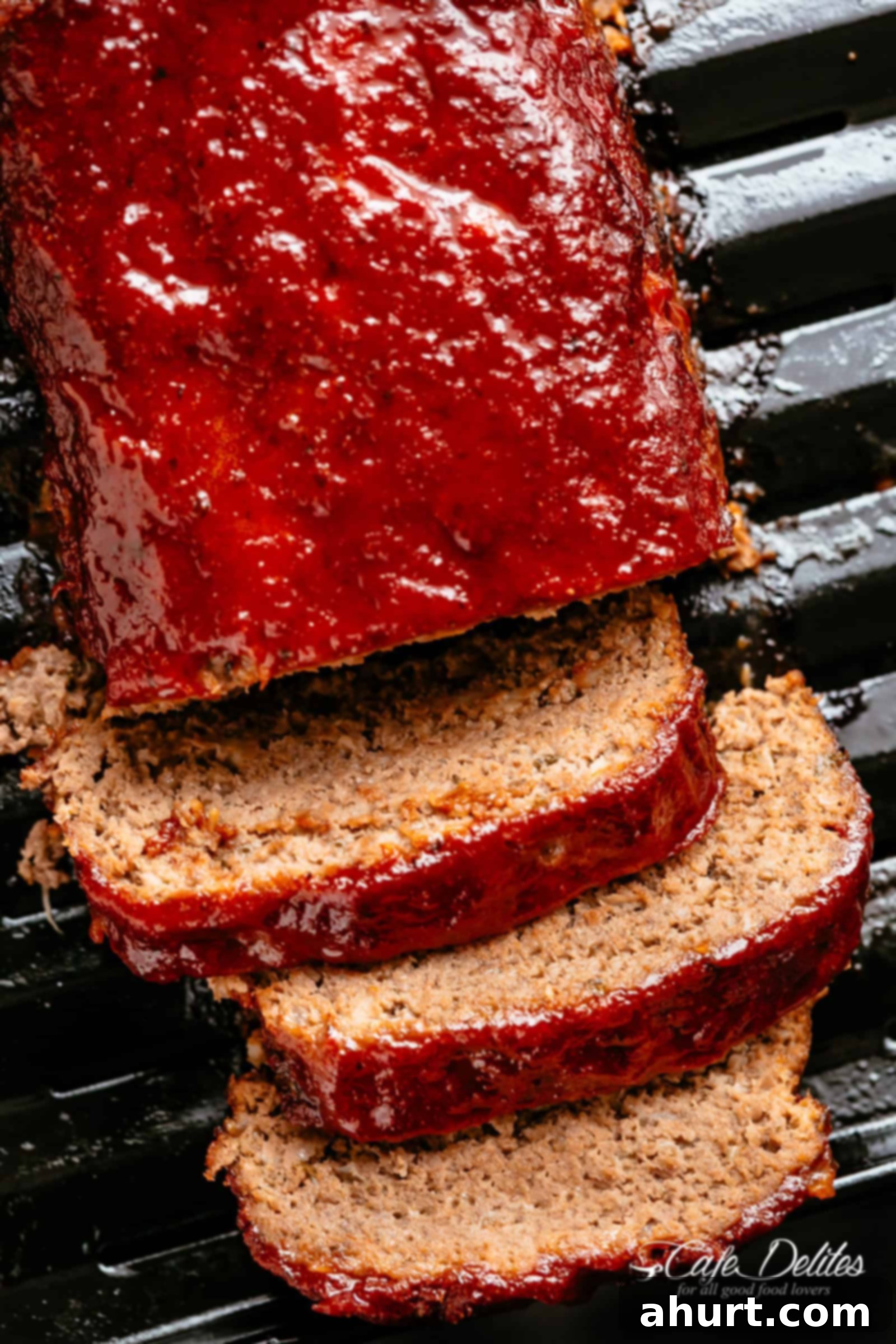 Meatloaf on a roasting tray #cafedelites #meatloaf #recipe #best Bird's eye view of grilled meatloaf on a grill, with three slices cut off the end.
