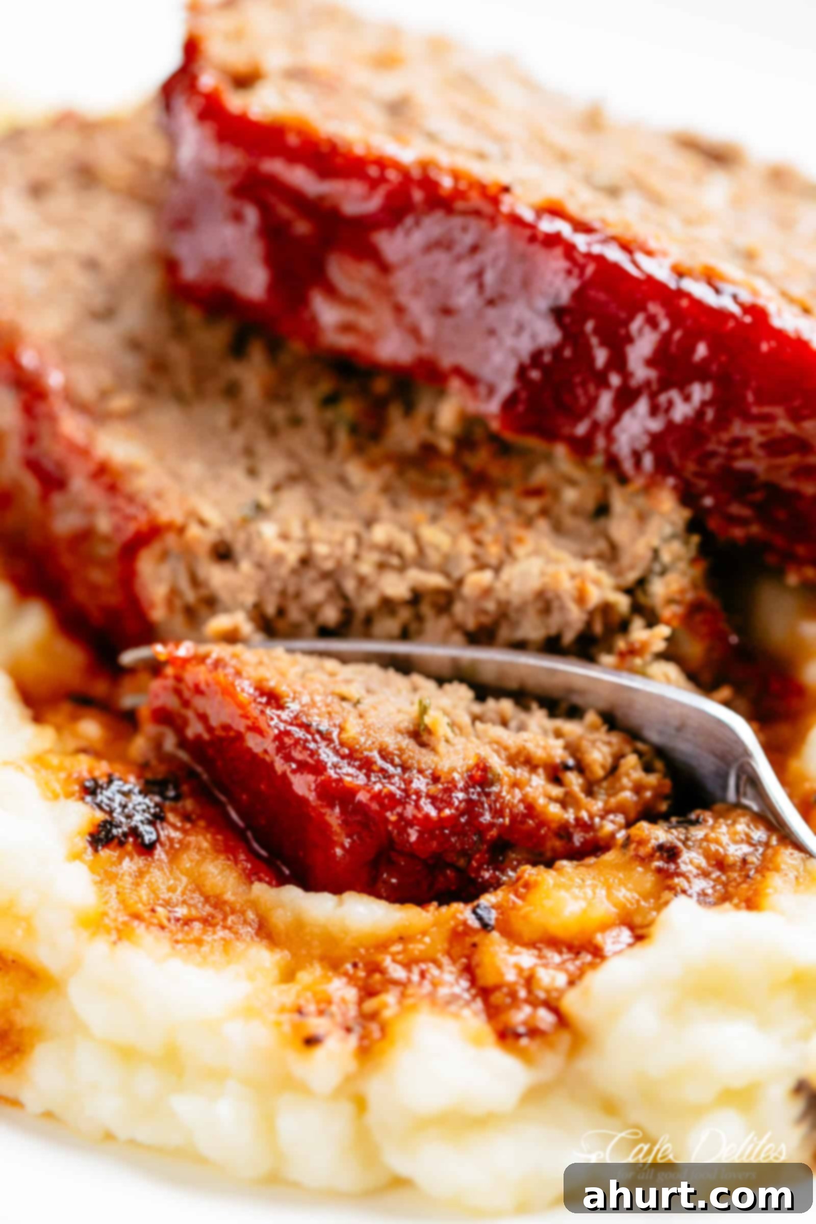 Meatloaf #cafedelites #meatloaf #mashedpotatoes Side view of Slicing through meatloaf and mashed potato with a fork.