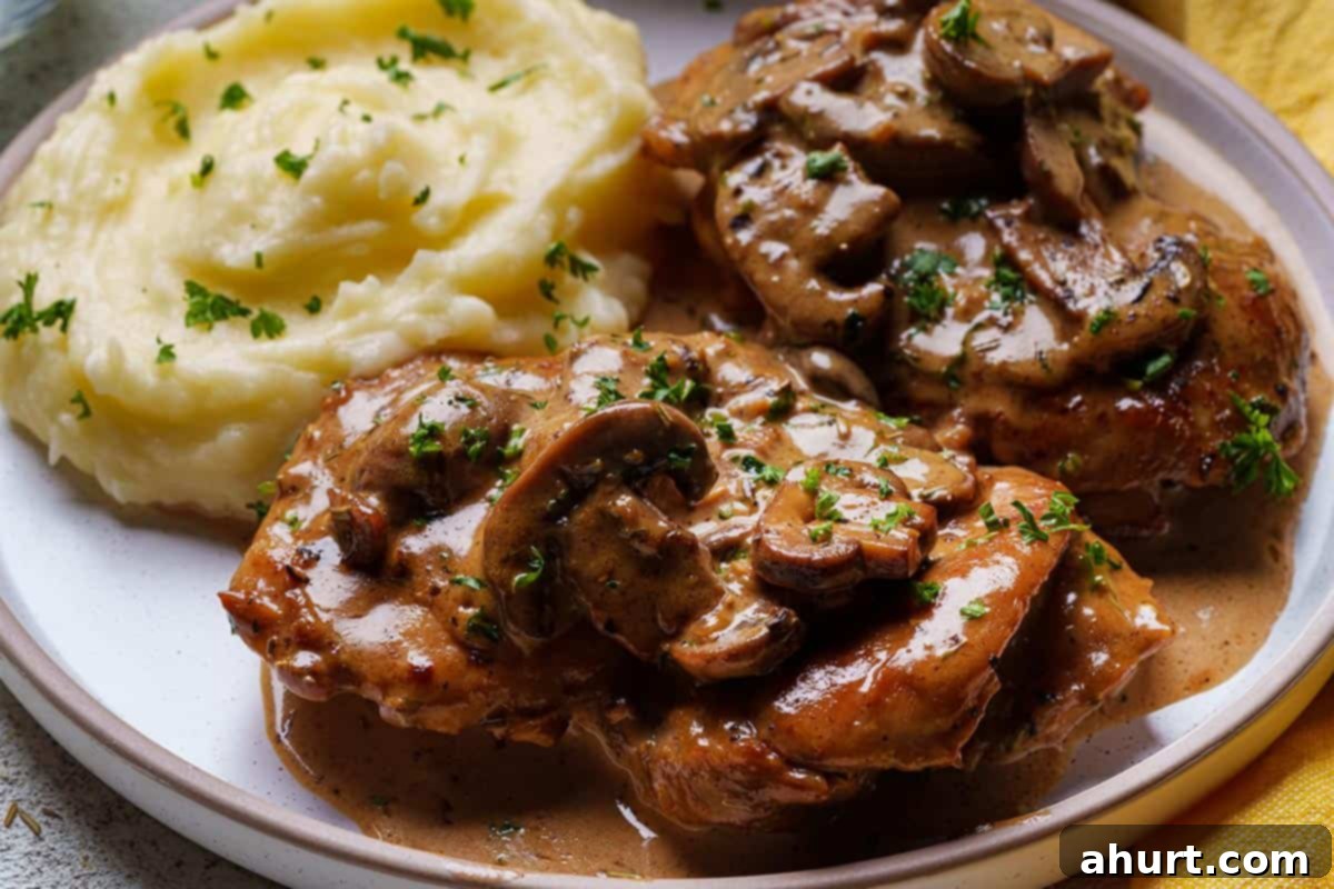 Creamy Mushroom Garlic Chicken Thighs 9 juicy mushroom chicken thighs sit on a plate with mashed potato as a side