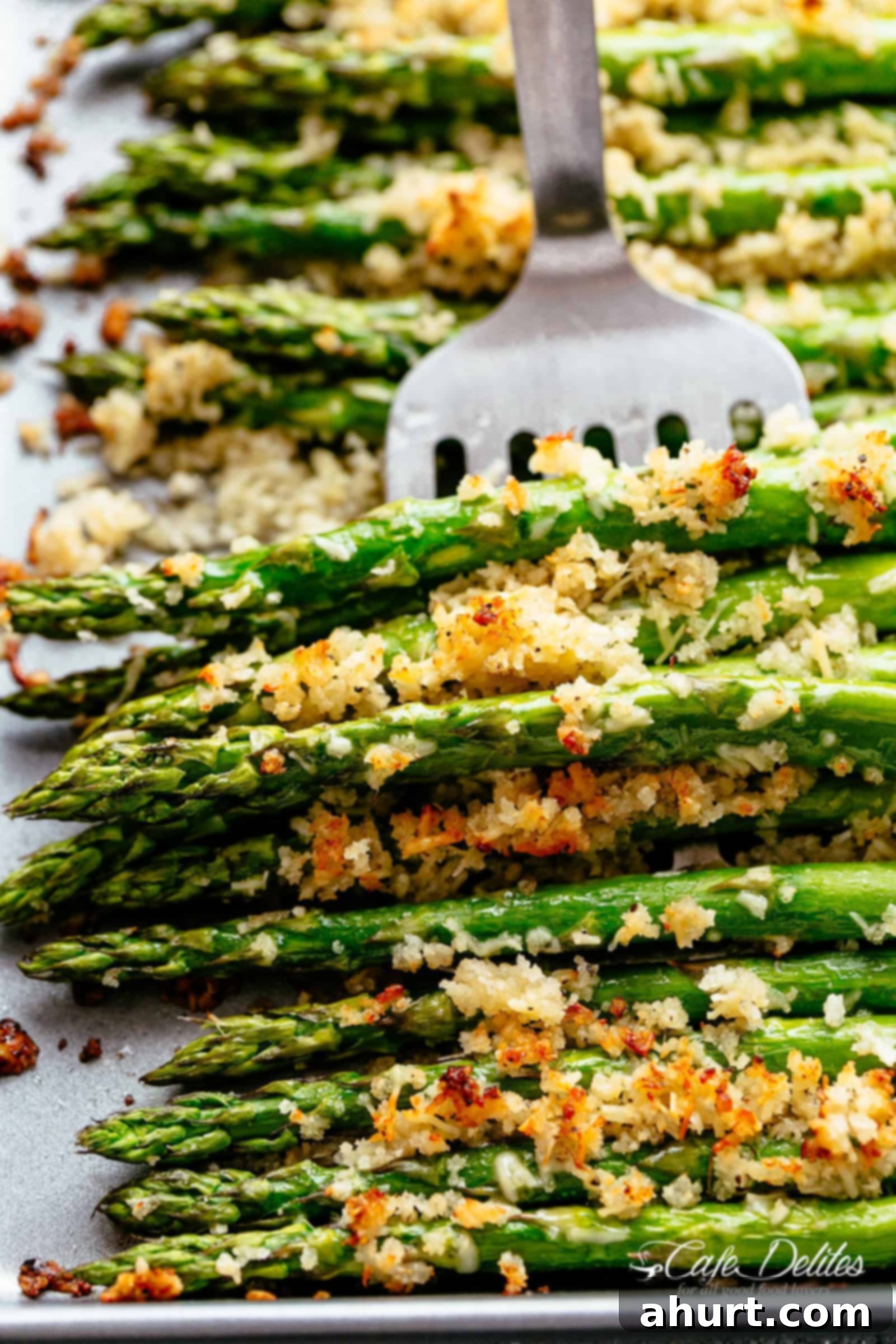 Parmesan Asparagus recipe! | cafedelites.com Garlic Butter Asparagus with Crispy Parmesan served on a white plate with a silver fork.