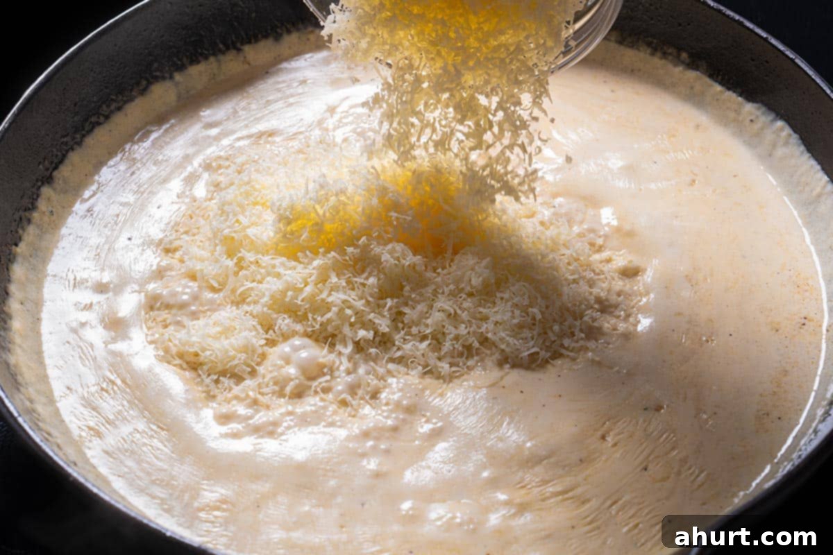 Luscious Low Carb Creamy Garlic Parmesan Shrimp 6 Parmesan is being added to the sauce.