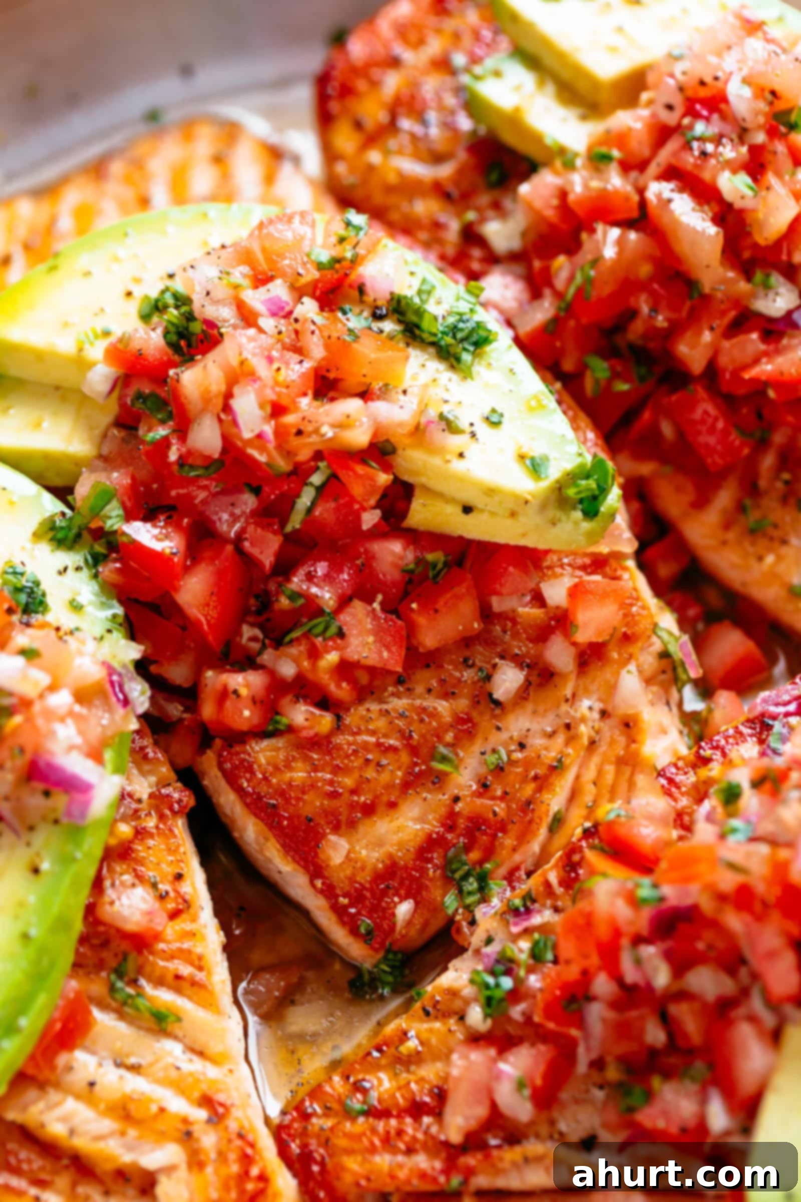 Pan seared salmon garnished with vibrant tomato salsa and creamy avocado slices, ready to serve.