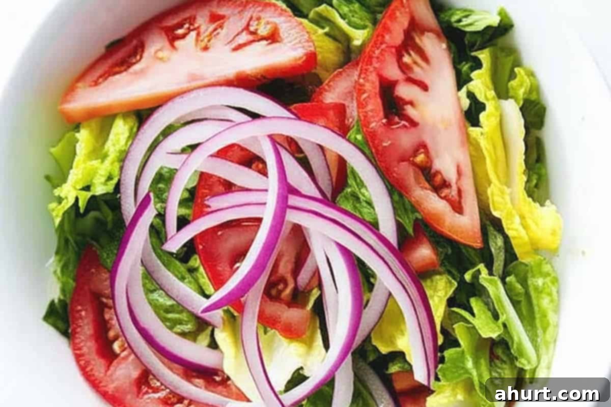 No-Fuss Tomato Salad 4 Step 1: Combining sliced ripe tomatoes, shredded romaine lettuce, and thinly sliced red onion in a large salad bowl, ready for dressing.
