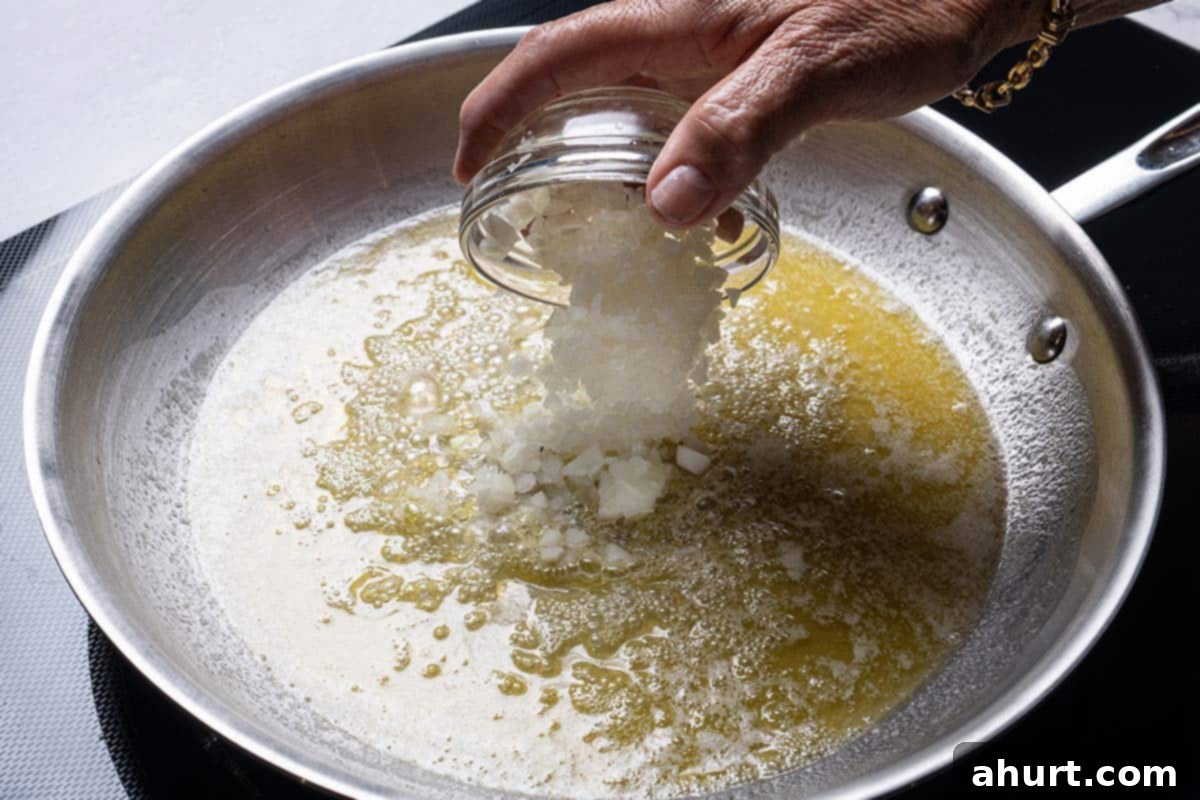 Golden Garlic Butter Mushrooms 4 An image of onions being added to the pan containing oil and butter that are frying.