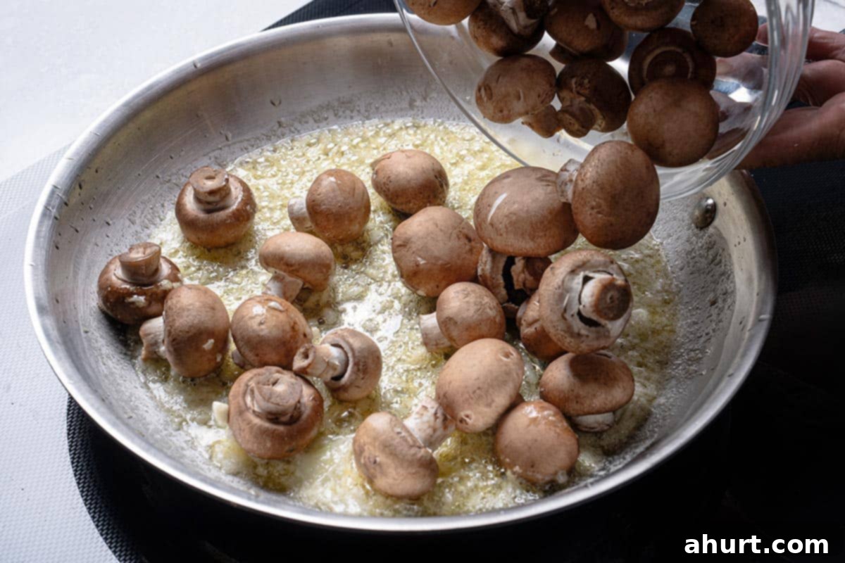 Golden Garlic Butter Mushrooms 5 An image shows onions being added to a pan containing oil and butter that are frying.