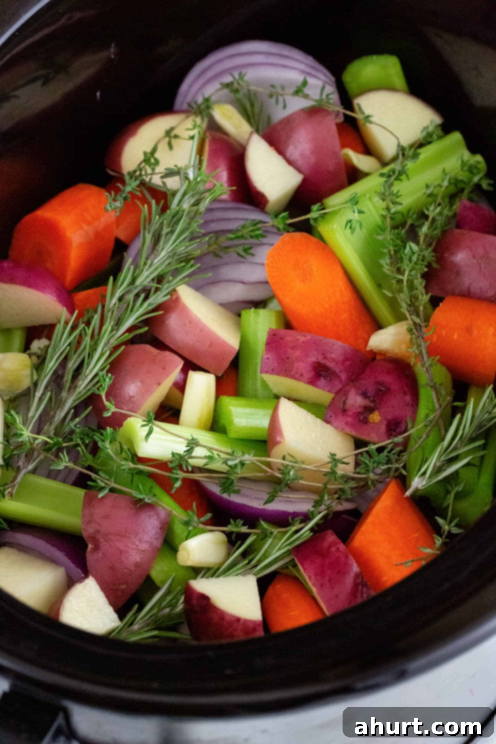 The Best Slow Cooker Whole Chicken 3 Raw Vegetables pieces in a pan, ready for slow cooking