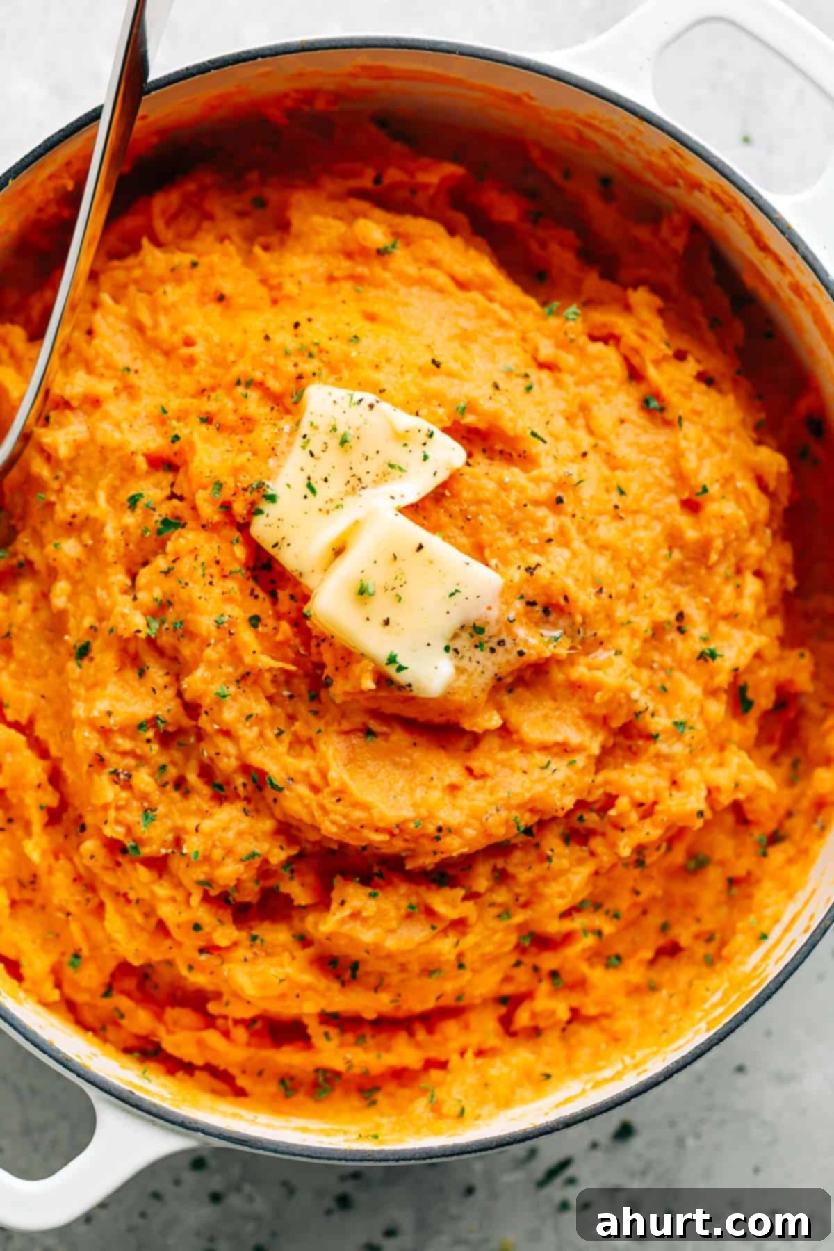 Garlic Herb Savory Sweet Potato Mash 2 Mashed Sweet Potatoes in a pan topped with butter pieces