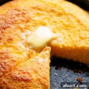 The Ultimate Recipe for Melt-in-Your-Mouth Cornbread 10 Cornbread with a triangle slice missing and melting butter cube in top in the centre in a cast iron pan