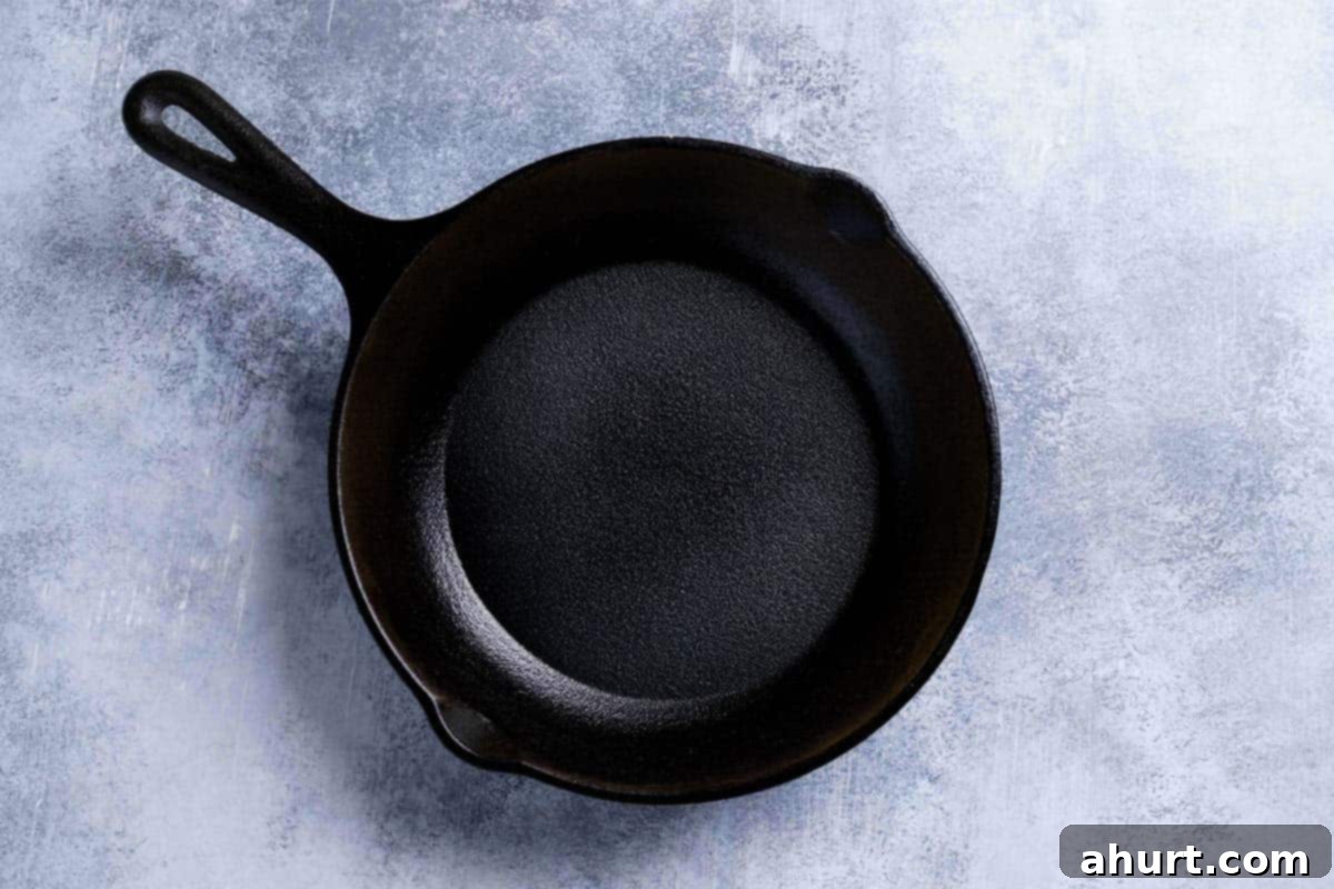The Ultimate Recipe for Melt-in-Your-Mouth Cornbread 3 A picture showing a greased skillet on a white marble surface being ready to be put into the oven for heating.