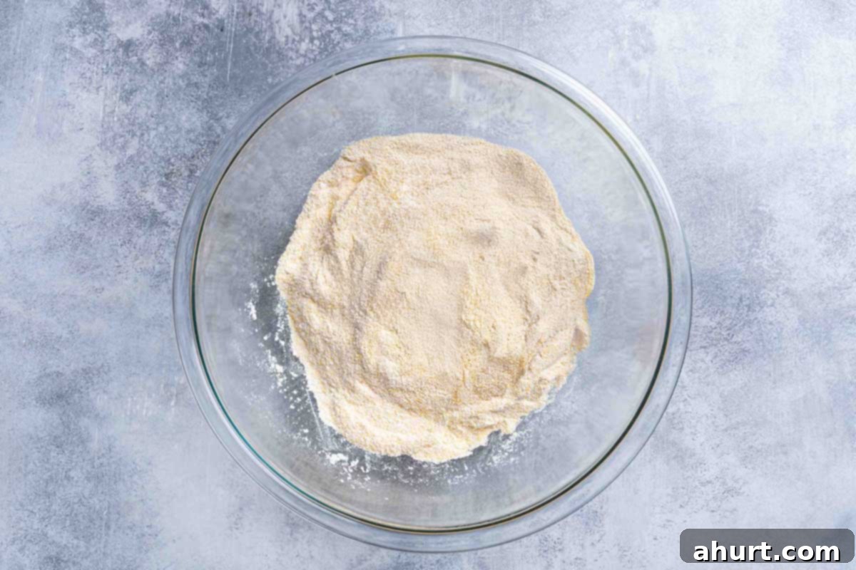 The Ultimate Recipe for Melt-in-Your-Mouth Cornbread 4 A picture shows polenta, flour, baking powder, baking soda, salt, and sugar mixed in a clear mixing bowl, representing the dry ingredients.