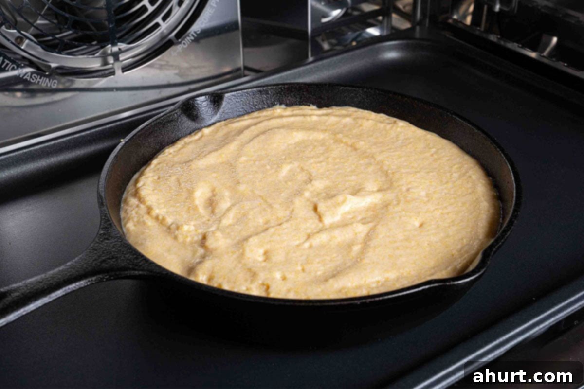 The Ultimate Recipe for Melt-in-Your-Mouth Cornbread 7 A picture of the skillet with the cornbread mixture, baked to a golden brown, being removed from the oven.