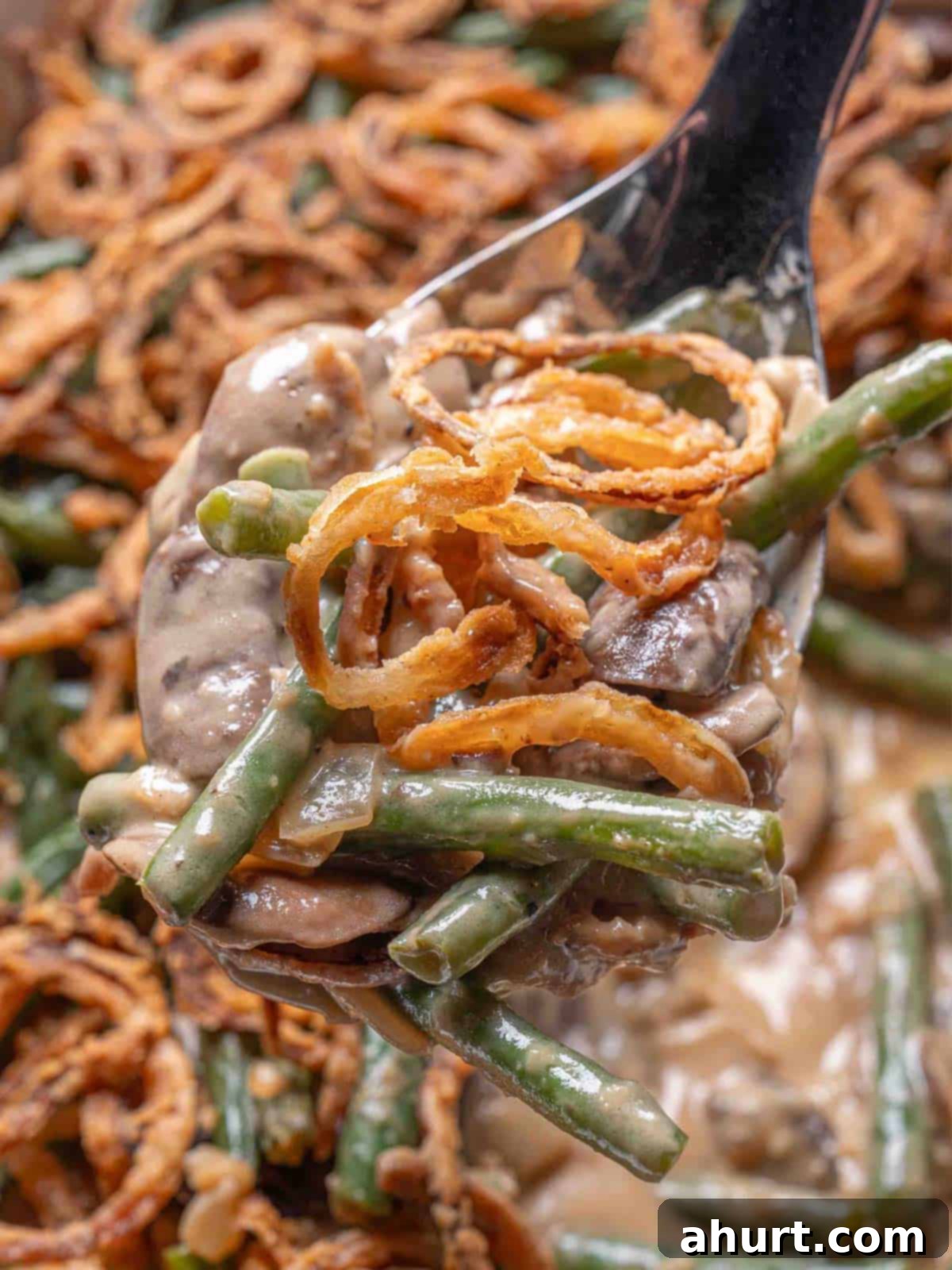 Velvety Green Bean Casserole with a Golden Crunch 12 spoon full of green bean casserole being held above the dish
