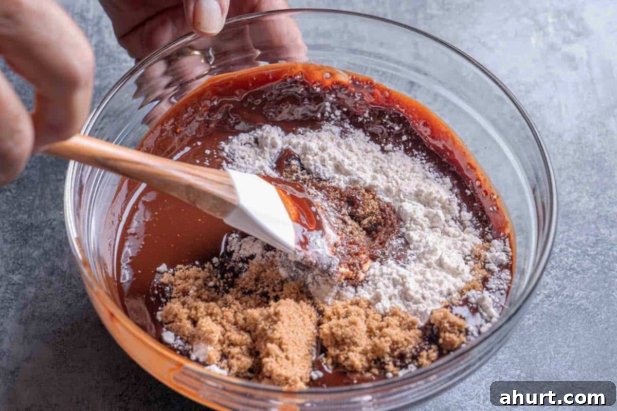 Decadent Chocolate Pecan Pie 6 A clear glass bowl filled with the rich, gooey chocolate pecan pie mixture, showing melted dark chocolate, butter, whisked eggs, corn syrup, brown sugar, and vanilla extract being combined.