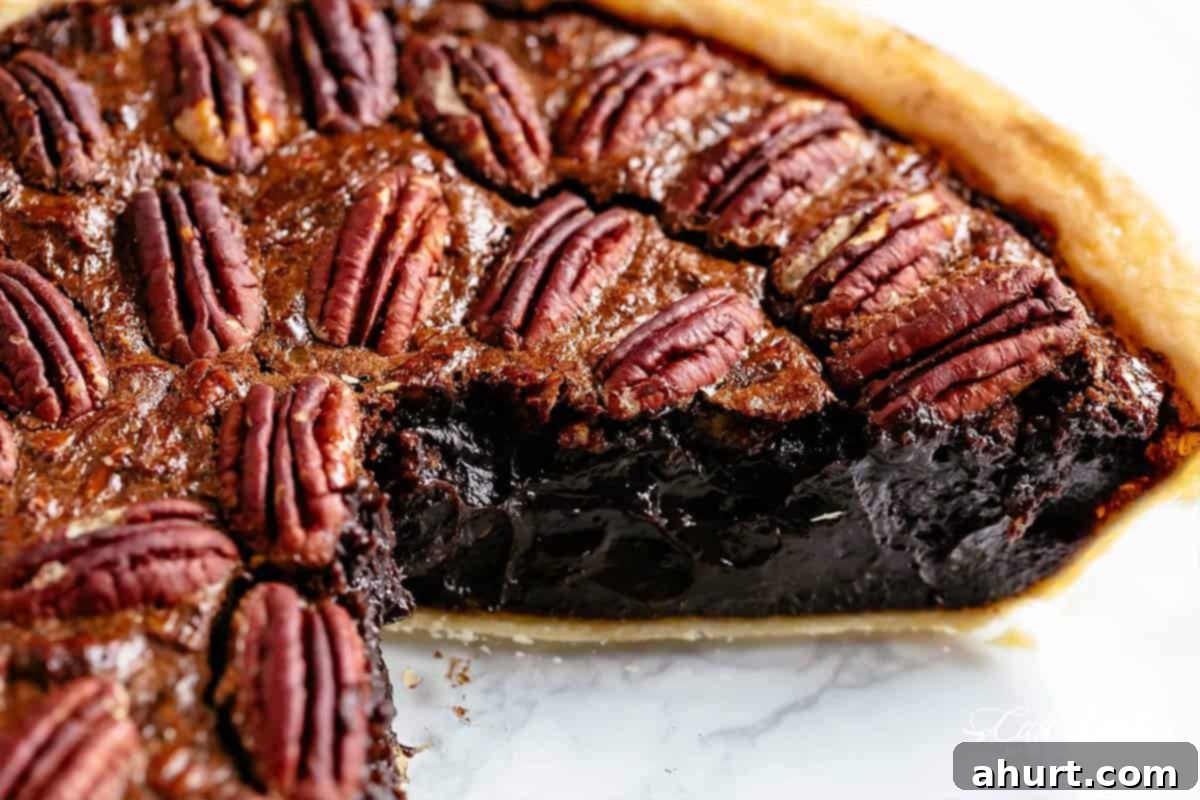 Decadent Chocolate Pecan Pie 9 A perfectly baked, rich brown chocolate pecan pie, cut in half to reveal its moist, fudgy, and gooey center filled with pecans and chocolate.