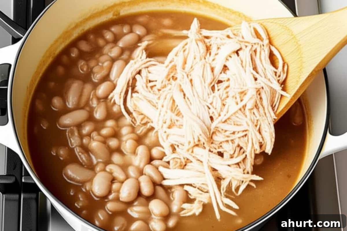 Hearty White Turkey Chili 5 Shredded turkey and white beans with stock in a pot.