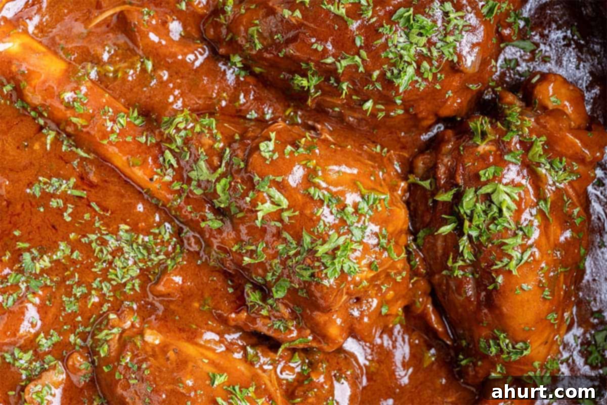 Fall-Off-The-Bone Lamb Shanks 11 A close-up shot of perfectly braised lamb shanks, garnished with fresh parsley and ready to serve.