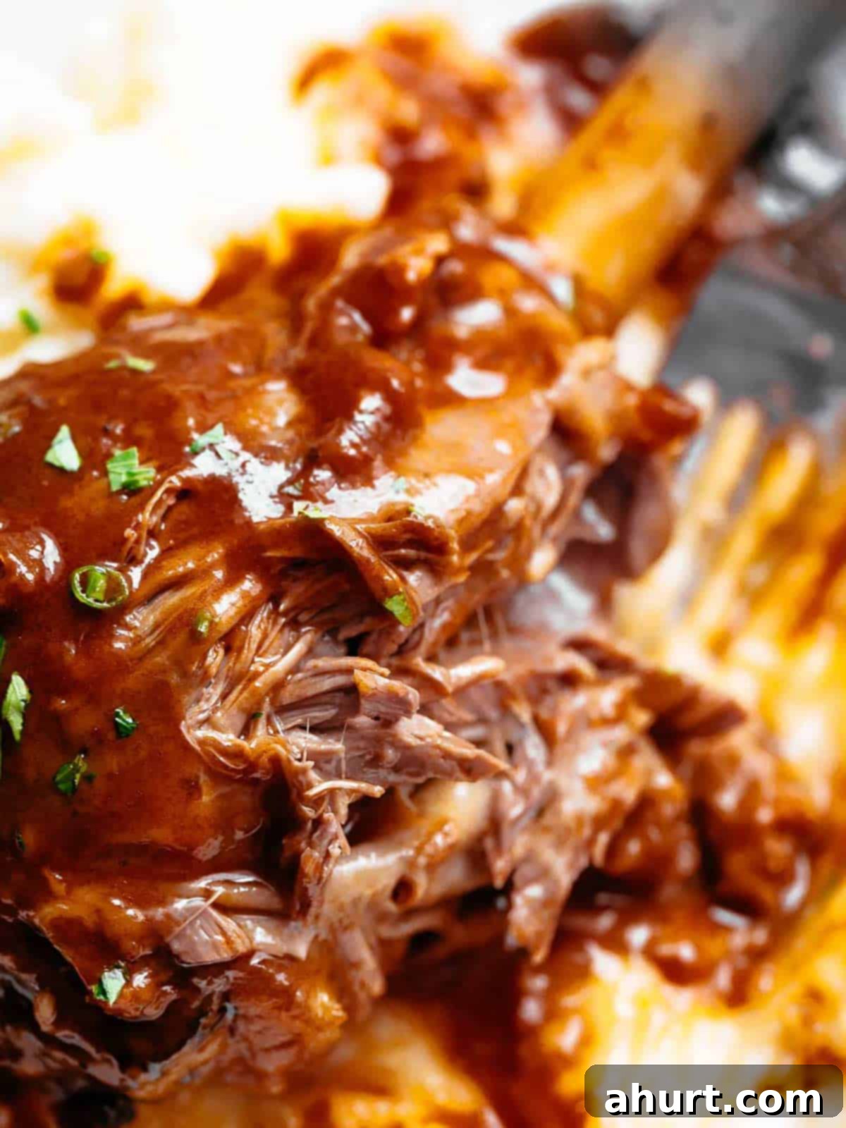 Fall-Off-The-Bone Lamb Shanks 12 Braised Lamb Shanks served on a bed of mashed potatoes, garnished with fresh herbs.