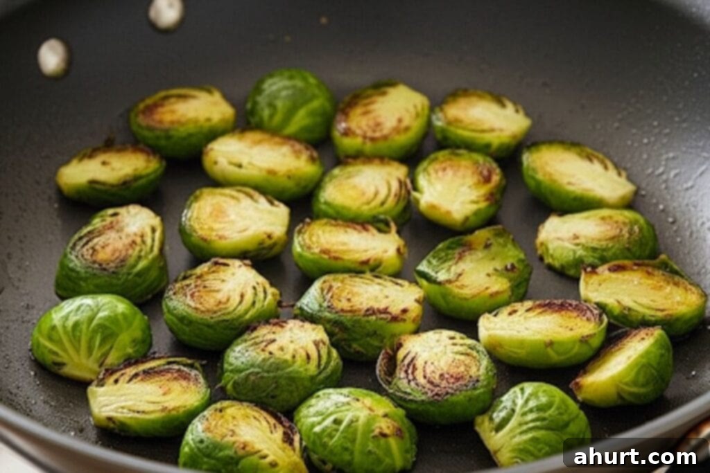 Cheesy Brussels Sprout Delight 5 Brussels sprouts searing cut-side down in a pan.