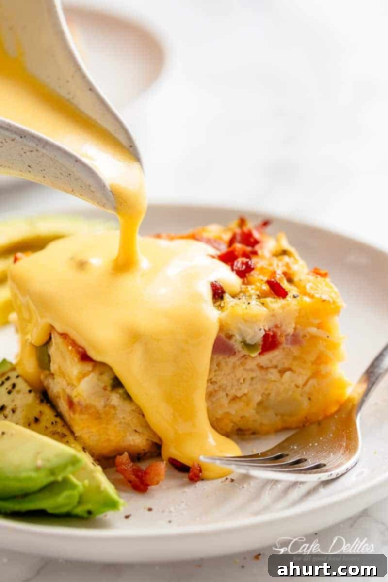breakfast casserole with hollandaise sauce #cafedelites #sauce #hollandaise #breakfast #casserole Creamy Hollandaise sauce being poured over a slice of breakfast casserole on a plate.